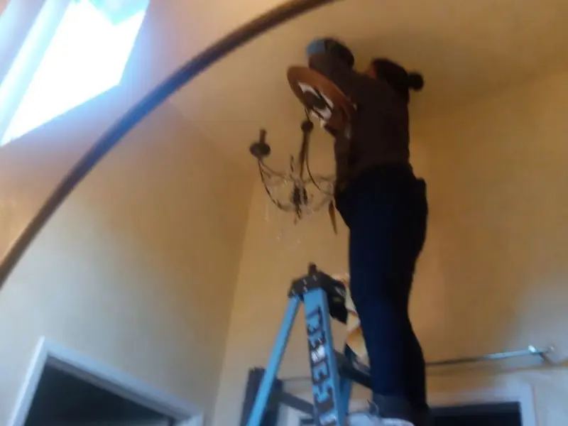 Electrician installing a chandelier in a Inkster residence